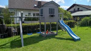 een speelhuis met een glijbaan en een speeltuin bij Ferienwohnung Haus Schmitt in Winterberg