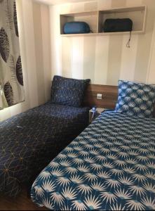 - une petite chambre avec un lit et une couette bleue dans l'établissement Camping à la Cotinière-Piscine-Bungalow cosy entre Océan et Pinède, à La Cotinière