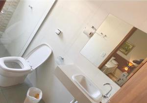a bathroom with a toilet and a sink and a mirror at Hotel Avenida in Jacarèzinho