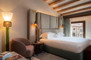 威尼斯Ca'di Dio-Small Luxury Hotel的一间卧室，里面有一张床、一把椅子和一扇窗户