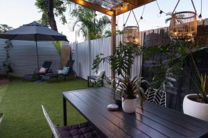 einen Terrassentisch mit Pflanzen und einem Sonnenschirm in der Unterkunft The Tropicana Courtyard in Cairns North