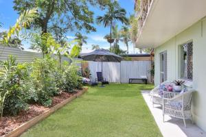 einen Garten mit Gras und Pflanzen und ein Haus in der Unterkunft The Tropicana Courtyard in Cairns North