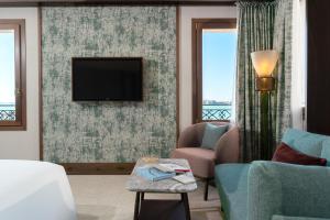 a living room with a tv and a couch and chairs at Ca'di Dio-Small Luxury Hotel in Venice