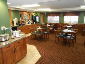 a restaurant with wooden tables and chairs and a kitchen at AmericInn by Wyndham McAlester in McAlester