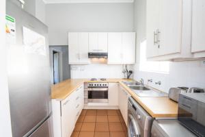 a kitchen with white cabinets and a stove top oven at Plettenberg Bay Unit J6 Goose Valley Apartment in Plettenberg Bay