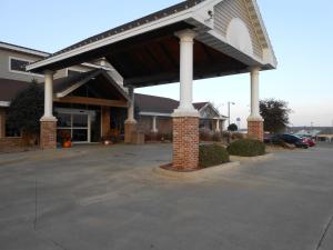 un grand parking avec un bâtiment doté d'un garage dans l'établissement AmericInn by Wyndham McAlester, à McAlester