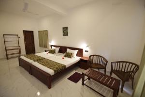 a bedroom with a large bed and two chairs at Mailagama Cinnamon Residence in Kataragama