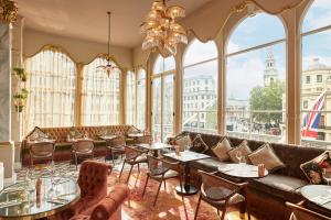un restaurante con mesas, sillas y ventanas grandes en The Clermont London, Charing Cross en Londres