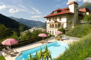 a house with a swimming pool and two umbrellas at Villa Excelsior Hotel & Kurhaus in Bad Gastein