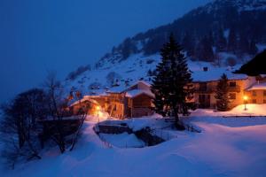 Una casa en la nieve por la noche en Hotel Ristoro Vagneur, en Saint Nicolas