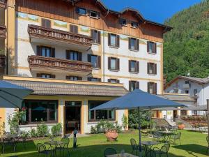 a large building with tables and chairs and an umbrella at Hotel Posta in Aprica