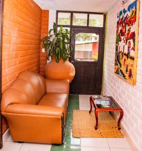 a living room with a leather couch and a plant at Alisamay Hotel in Baños