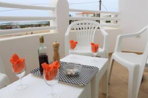a table with two white chairs and a bottle of wine at African Sunset in Sal Rei