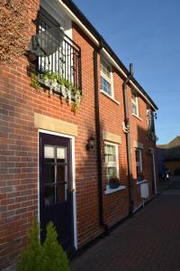 a brick building with a blue door and a balcony at Frinton Escapes - The Cottage in Frinton-on-Sea