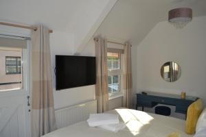 1 dormitorio con 1 cama y TV en la pared en Frinton Escapes - The Cottage, en Frinton-on-Sea