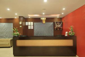 a waiting room with a reception desk and red wall at La Sara Hometel in Bangalore