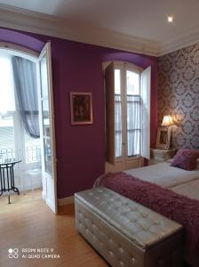 a bedroom with purple walls and a bed with a couch at Alojamiento Buciero in Santoña