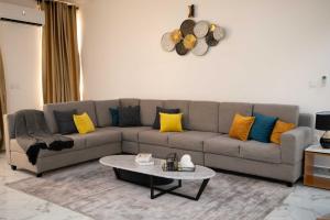 uma sala de estar com um sofá cinzento com almofadas amarelas e azuis em Kay's Comfort Place em Lekki