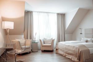 um quarto com uma cama, 2 cadeiras e uma janela em Clostermanns Hof em Niederkassel