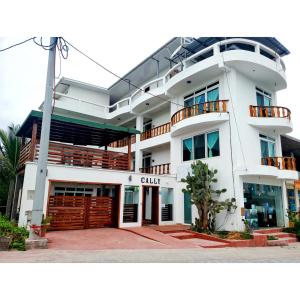 - un grand bâtiment blanc avec une porte devant dans l'établissement Hotel Cally, à Puerto Villamil
