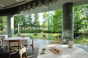 a restaurant with white tables and chairs and a large window at Bellino Hotel Ichinoseki in Ichinoseki
