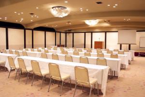 uma sala de conferências com mesas e cadeiras brancas e um pódio em Hotel Matsunoka Ichinoseki em Ichinoseki