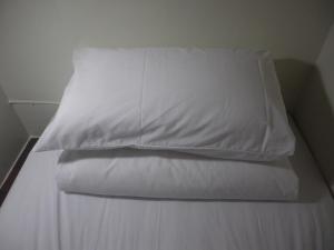 una cama con una almohada blanca encima en Herbaceous-Inn, en Nanwan