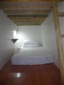 Cama blanca en habitación con techo de madera en Herbaceous-Inn, en Nanwan