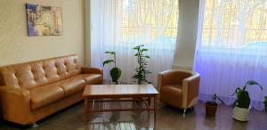 uma sala de estar com um sofá, uma cadeira e uma mesa em Gostinochyi Kompleks Hillary em Temirtaū