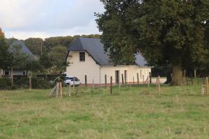 una casa blanca con una valla en un campo en "Chez Michel " Les Gîtes de Séry, en Bouillancourt-en-Séry