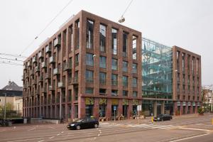 un gran edificio de ladrillo con coches estacionados frente a él en Amadi Park Hotel en Ámsterdam