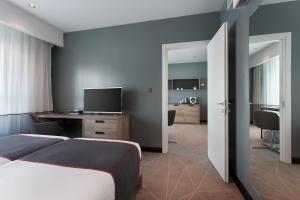 a bedroom with a bed and a desk with a television at be.HOTEL in St. Julianʼs