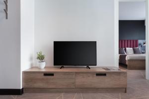 a living room with a flat screen tv on a wooden entertainment center at be.HOTEL in St. Julianʼs