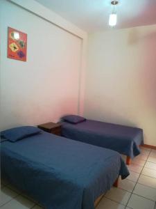2 Betten in einem Zimmer mit blauer Bettwäsche in der Unterkunft JUMANA in Nazca