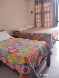 1 dormitorio con 2 camas y edredón colorido en Apartamento Taperapuan, en Porto Seguro