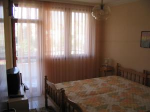a bedroom with a bed and a window with curtains at Guest House Preslav in Nesebar