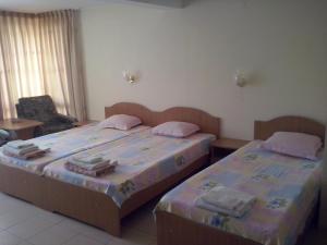 a bedroom with two beds and a chair at Guest House Preslav in Nesebar