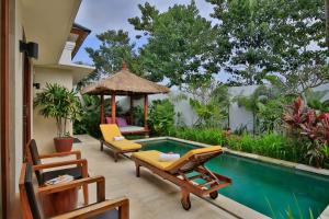 um quintal com uma piscina, cadeiras e uma mesa em Villa Anandani em Ubud