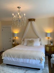 a bedroom with a large white bed with a chandelier at Beach Street Inn in St. Martins