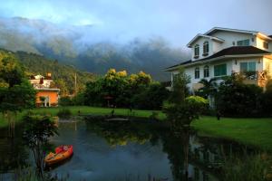 a house and a boat in the water next to a house at Tree Lake B&B Hualien in Shuhu