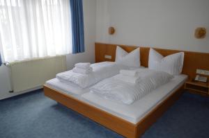 ein großes Bett mit weißer Bettwäsche und Kissen darauf in der Unterkunft Gasthof Hotel Löwen in Bad Buchau
