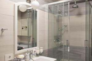 ein Badezimmer mit Dusche, Waschbecken und Spiegel in der Unterkunft Căsuța din Copou in Iaşi