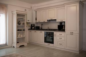 a white kitchen with white cabinets and a stove at Căsuța din Copou in Iaşi