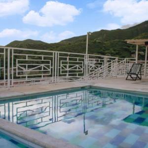 a swimming pool with a fence and a chair at Hostel Green Light in Taganga