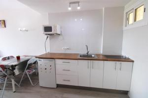 uma cozinha com armários brancos, um lavatório e uma mesa em Jupiter Apartments Sea View em Benalmádena