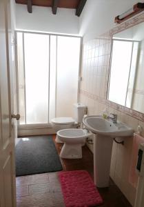 a bathroom with a sink and a toilet and a mirror at Santa Maria do Mar Guest House in Peniche