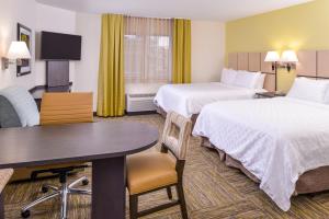 Cette chambre comprend 2 lits et une table. dans l'établissement Candlewood Suites - Plano North, an IHG Hotel, à Plano
