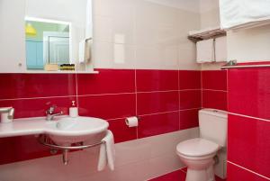 a red and white bathroom with a toilet and a sink at Mirella Studios in Loutra Oraias Elenis  +47 photos