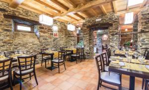 restauracja ze stołami i krzesłami w kamiennej ścianie w obiekcie Finca O Bizarro w mieście Trabada