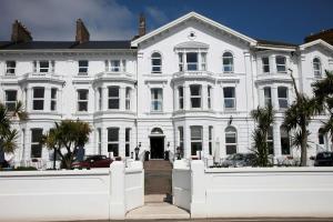 a white house with a white fence in front of it at Exmouth Beach Hotel in Exmouth